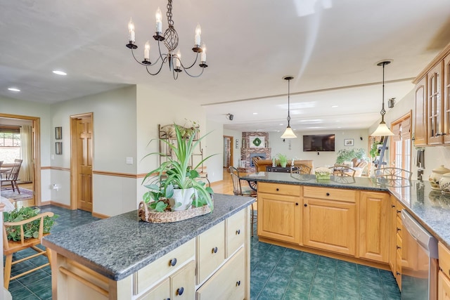 kitchen with dishwasher, hanging light fixtures, a kitchen island, light brown cabinetry, and dark stone counters