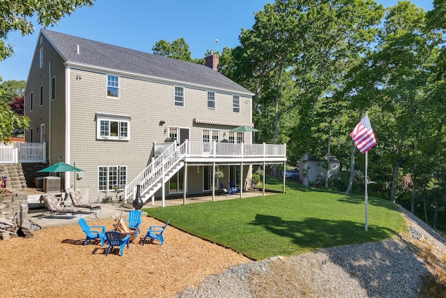 rear view of property with a wooden deck, a yard, a patio area, and an outdoor fire pit