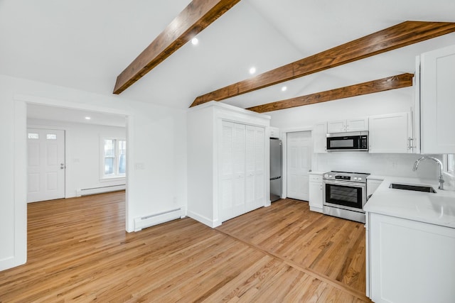 kitchen with a sink, stainless steel appliances, baseboard heating, and light countertops