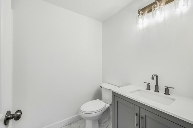 bathroom with baseboards, toilet, marble finish floor, and vanity