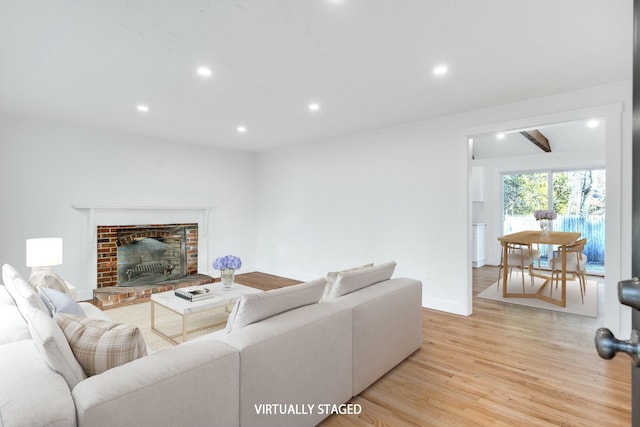 living area with light wood-style flooring, recessed lighting, a fireplace, and baseboards