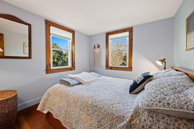 bedroom with multiple windows, baseboards, and dark wood finished floors