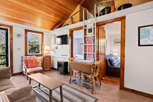 living area featuring vaulted ceiling, baseboards, a wood stove, wooden ceiling, and light tile patterned floors