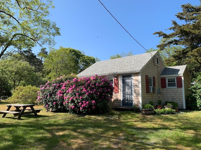 exterior space featuring cooling unit, a yard, and a shingled roof