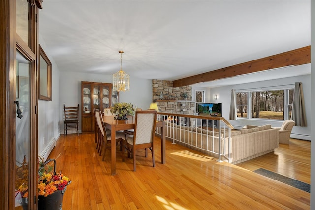 dining space featuring light wood-type flooring, a baseboard heating unit, and a notable chandelier