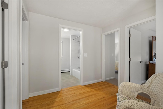 sitting room featuring baseboards, light wood-style flooring, and baseboard heating