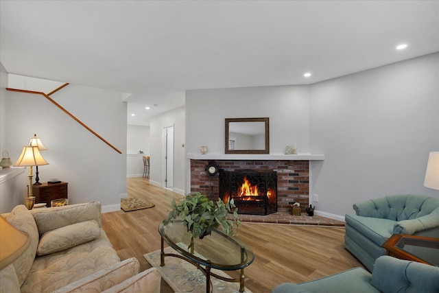 living room featuring a fireplace, baseboards, wood finished floors, and recessed lighting