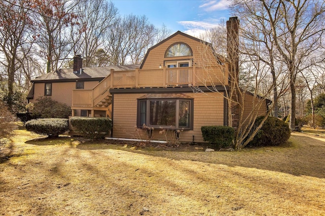 rear view of house with a deck, a chimney, and stairs