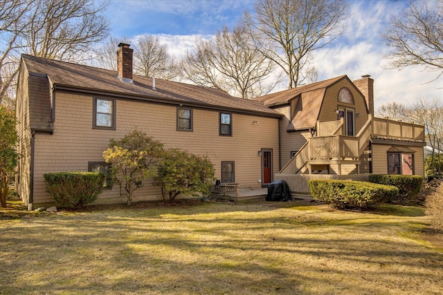 back of house with a lawn, roof with shingles, a chimney, and a gambrel roof