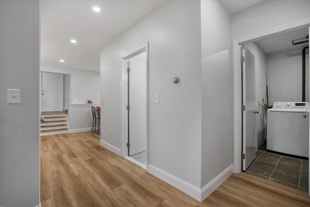 hallway featuring baseboards, wood finished floors, washer / dryer, and recessed lighting