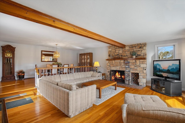 living area featuring light wood-style floors, a fireplace, baseboards, and beamed ceiling