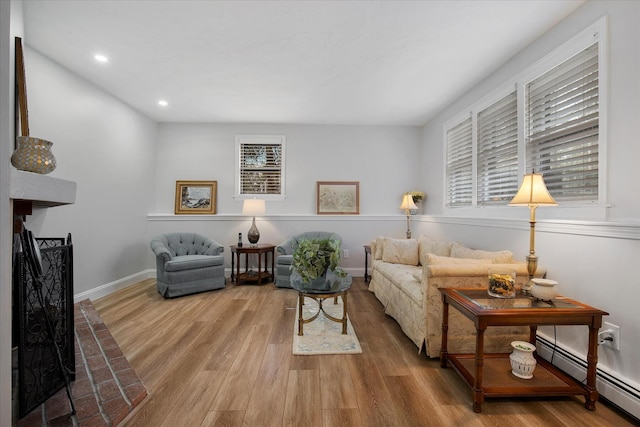 sitting room with plenty of natural light, a baseboard radiator, wood finished floors, and baseboards