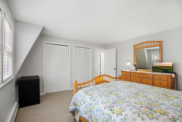 carpeted bedroom with a baseboard heating unit and two closets