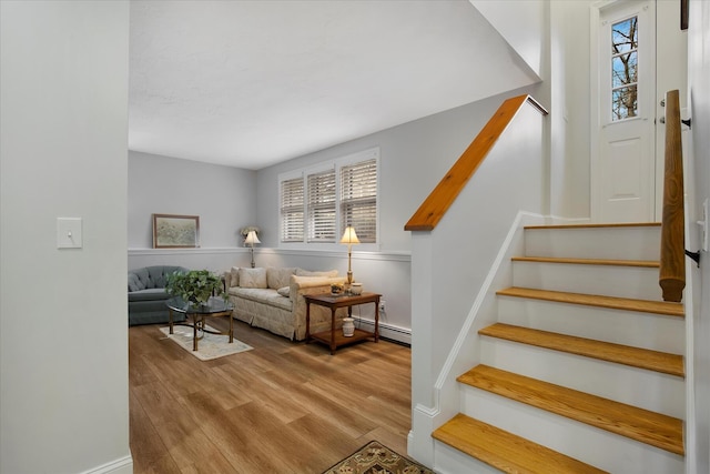 stairs featuring a baseboard heating unit and wood finished floors