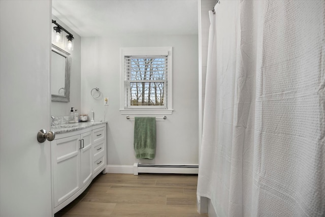 full bathroom with a baseboard heating unit, wood finished floors, vanity, and baseboards