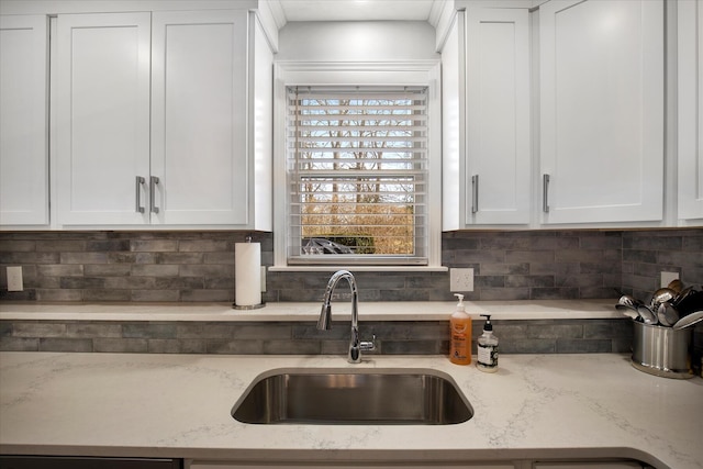 kitchen featuring tasteful backsplash, a sink, and white cabinetry