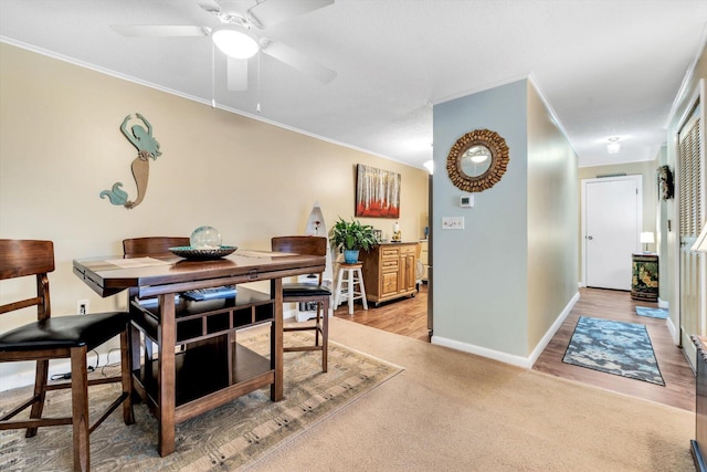 carpeted dining room with ornamental molding and ceiling fan