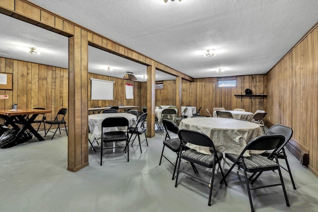 dining room featuring a textured ceiling and wooden walls