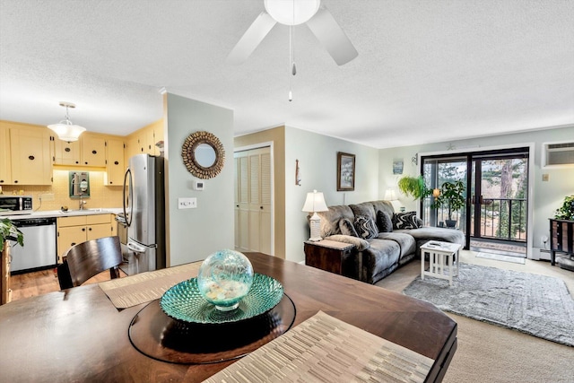 dining space featuring a baseboard radiator, sink, light colored carpet, a textured ceiling, and a wall unit AC