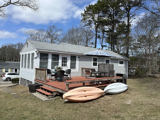 20 Uncle Percys Rd, Mashpee, MA 02649 - rear view of house with roof with shingles, a wooden deck, outdoor dining area, and a lawn