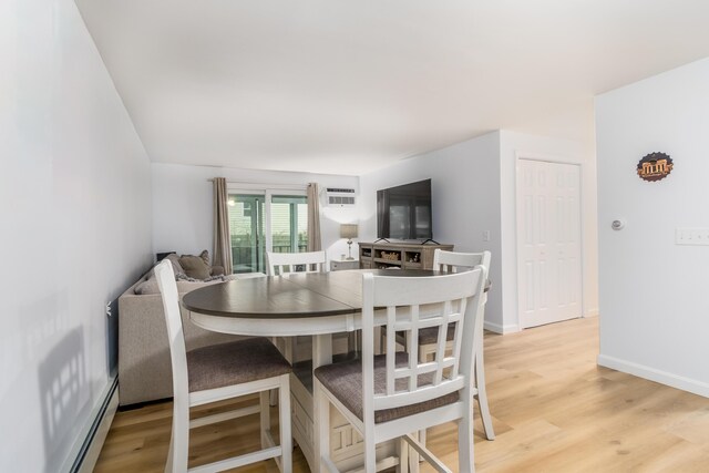 dining area featuring light hardwood / wood-style floors, a baseboard heating unit, and a wall unit AC