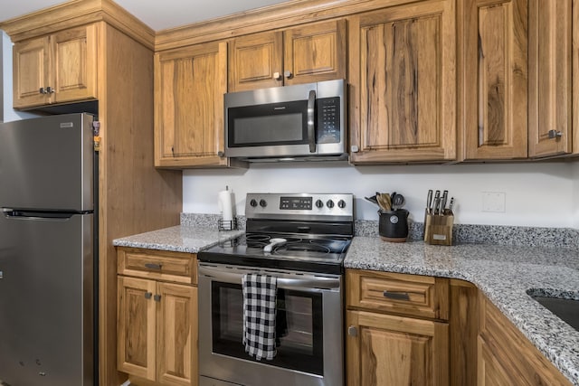 kitchen with light stone counters and appliances with stainless steel finishes