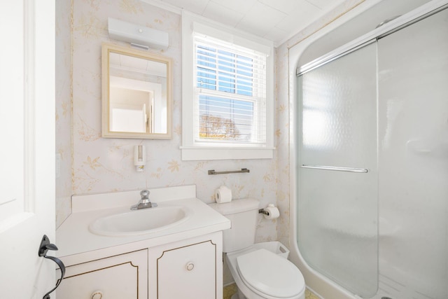 bathroom with toilet, wallpapered walls, a shower stall, vanity, and a wall mounted AC