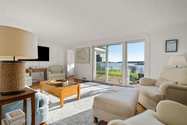 living room featuring wood finished floors, visible vents, and a water view