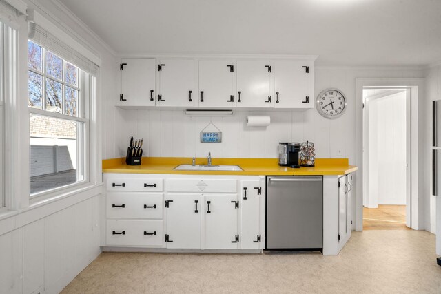 kitchen featuring crown molding, a sink, dishwasher, light countertops, and white cabinets
