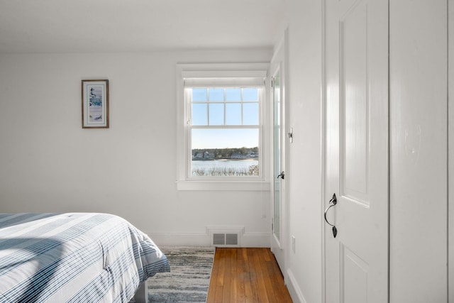 bedroom with baseboards, visible vents, and wood-type flooring