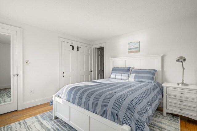 bedroom with baseboards, wood finished floors, and a closet