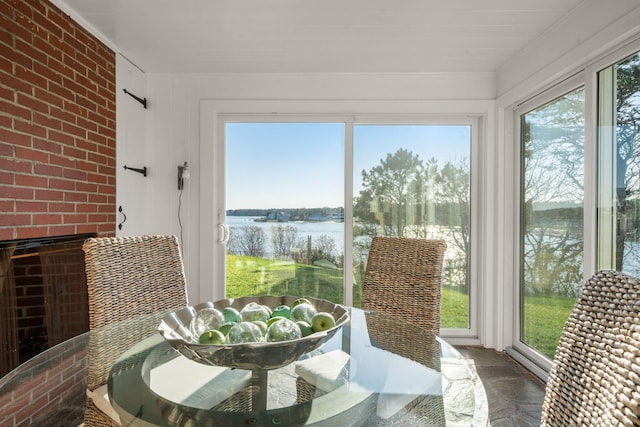 sunroom featuring a water view, ornamental molding, and brick wall