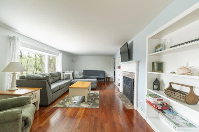 dining space with visible vents, a tiled fireplace, built in features, a wainscoted wall, and wood-type flooring