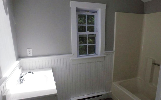 full bathroom featuring a wainscoted wall,  shower combination, a baseboard radiator, and a sink