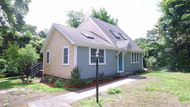 view of front facade featuring a shingled roof and a front yard