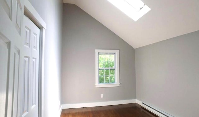 bonus room featuring vaulted ceiling with skylight, a baseboard heating unit, dark wood finished floors, and baseboards