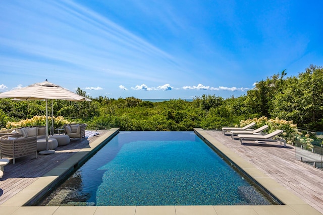 view of pool featuring an outdoor hangout area, an infinity pool, and a deck
