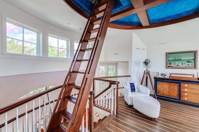 stairway with wood finished floors, beam ceiling, and coffered ceiling