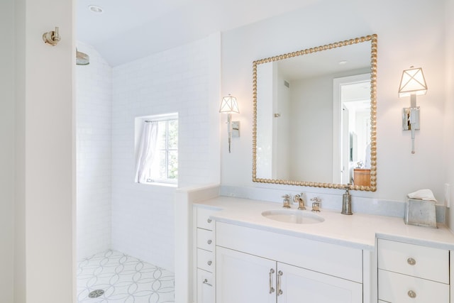full bathroom featuring a tile shower and vanity