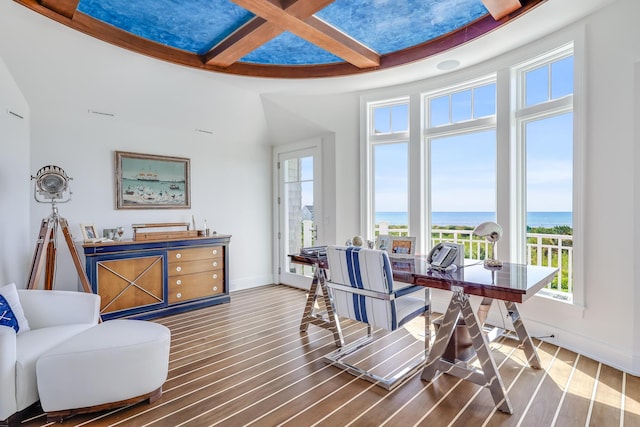 dining space featuring wood finished floors, a wealth of natural light, a water view, and coffered ceiling