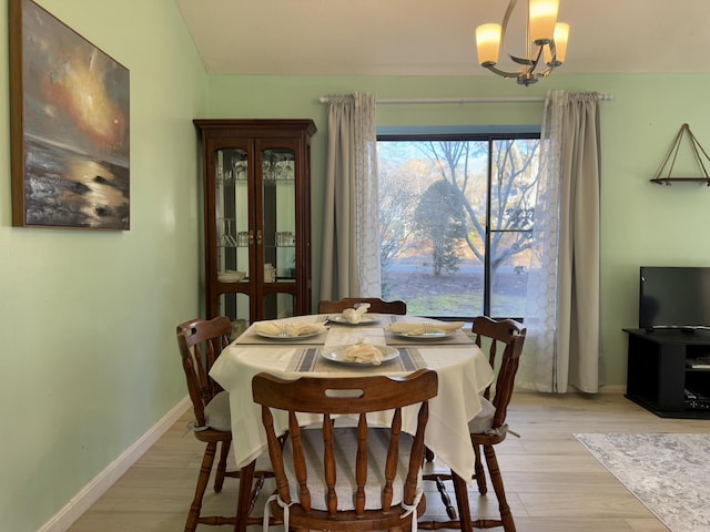 dining room featuring light wood finished floors, an inviting chandelier, and baseboards