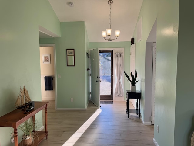 foyer with baseboards, light wood-style flooring, and an inviting chandelier