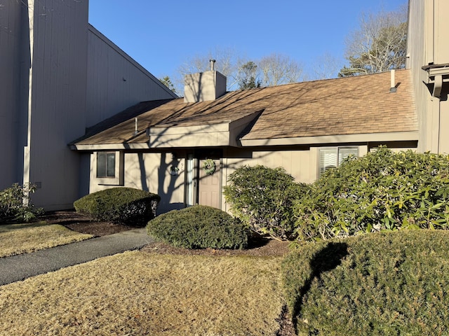 exterior space featuring a shingled roof and a chimney