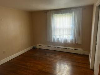 unfurnished room with a baseboard radiator and dark hardwood / wood-style flooring