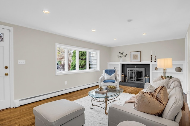 living room featuring light hardwood / wood-style floors, baseboard heating, and a tiled fireplace