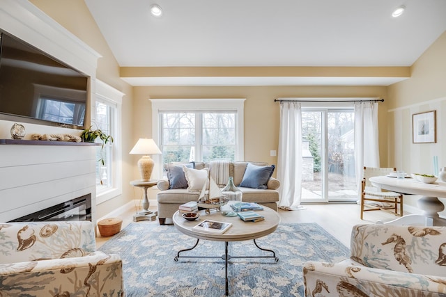 living area featuring recessed lighting, vaulted ceiling, wood finished floors, and a glass covered fireplace