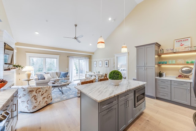 kitchen with light wood-style floors, stainless steel microwave, open floor plan, and gray cabinetry