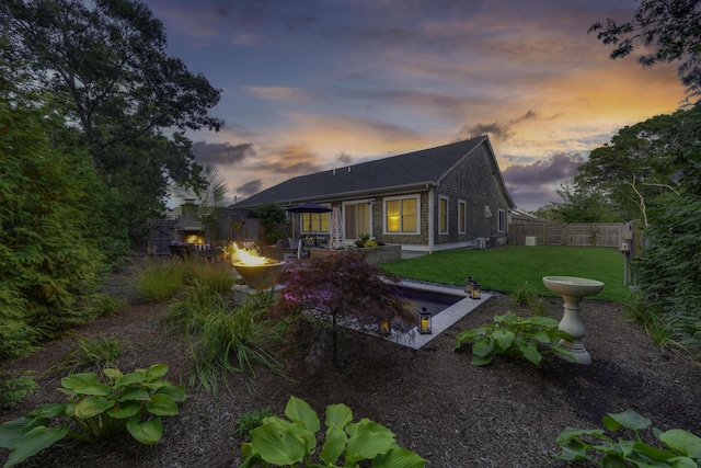 back of house with an outdoor fire pit, a lawn, a patio area, and a fenced backyard