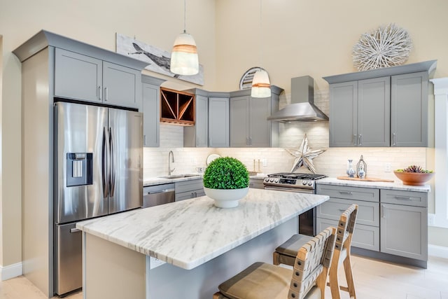 kitchen featuring a sink, stainless steel appliances, wall chimney range hood, and gray cabinets