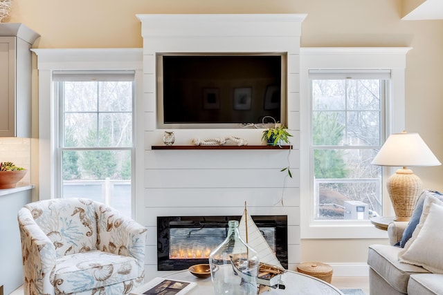 living area featuring baseboards and a glass covered fireplace